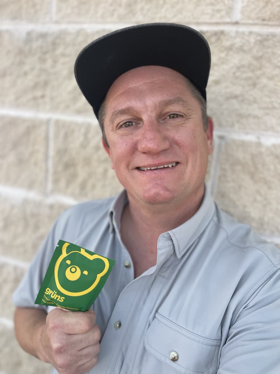 John smiling and holding a pouch of Grüns superfood greens gummies